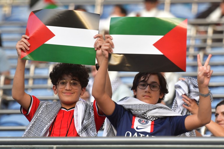 Los fanáticos palestinos sostienen banderas nacionales de Palestina antes de un partido de fútbol de clasificación contra Australia para la Copa Mundial de la FIFA 2026 en el estadio Jaber Al-Ahmad en Kuwait, el martes 21 de noviembre de 2023. (Foto AP/Jaber Abdulkhaleg)