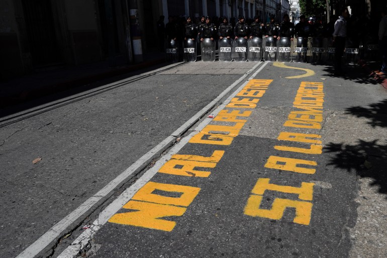 A roadway has yellow lettering written on its concrete, which reads: "No al golpe de estado. Si a la democracia."