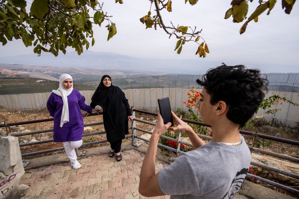 A boy takes a souvenir picture on his mobile phone to his family in front of a wall that build by Israel, background, in Odaisseh border village with Israel, south Lebanon.
