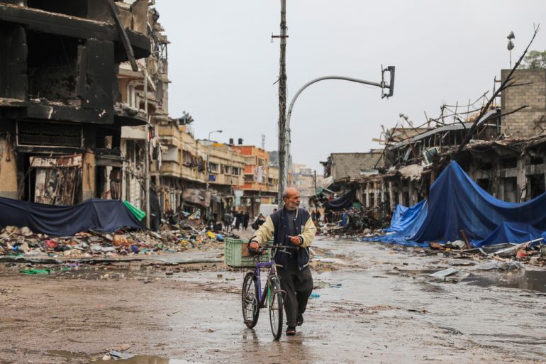 A man walks his bicycle through a heavily damaged Gaza City