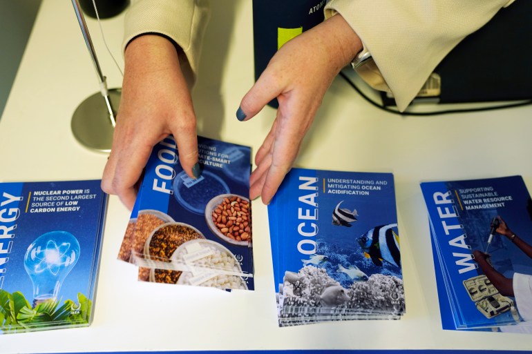 A pair of hands reaches down to rearrange stacks of brochures on a table. Some are labeled "ocean," "water" and "food."