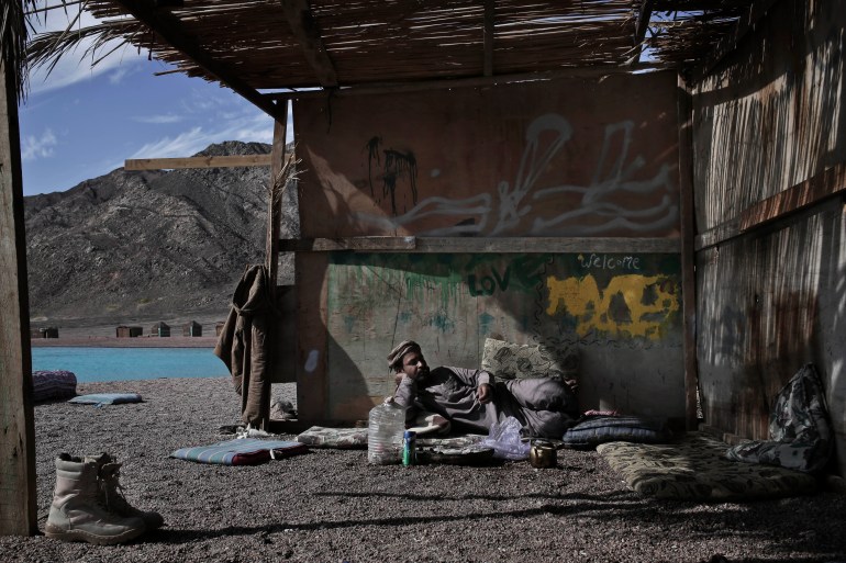 A Bedouin man rests inside an open-sided hut