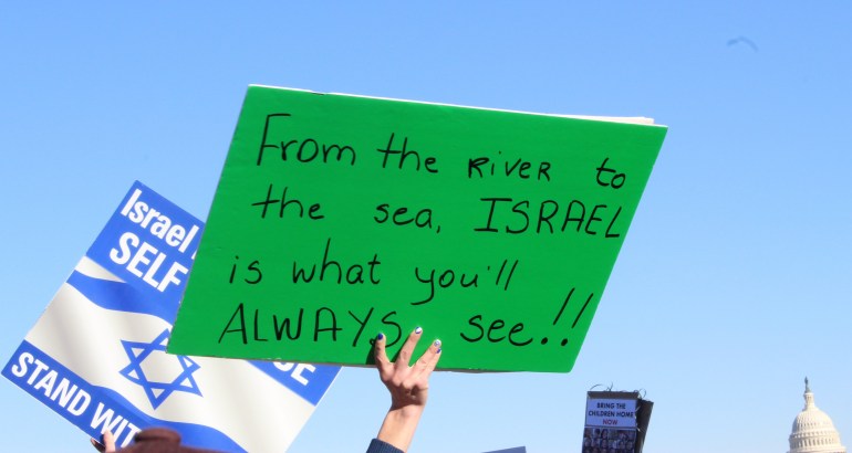Woman holds green sign that reads, "From the River to the Sea, Israel is what you will always see."
