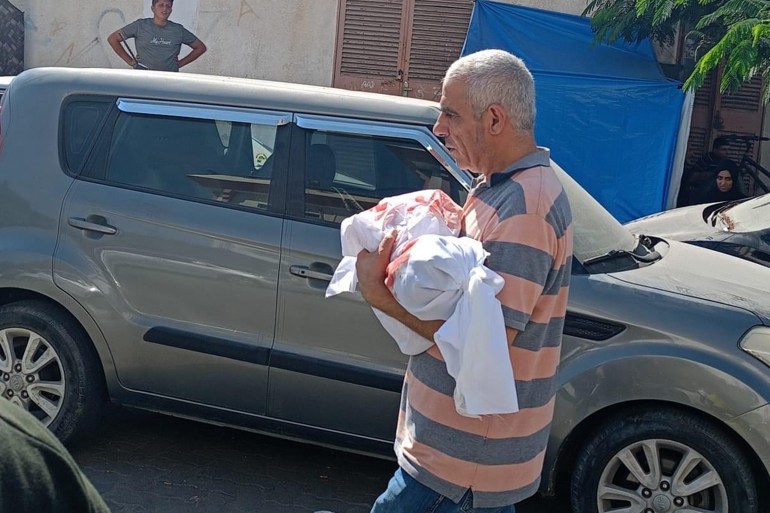 A man carrying the shrouded body of a child