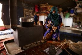 Wadha al-Yousef, 36, burns what scraps she can find to keep her five children warm in the family&#039;s tent at Kafr Yahmul camp in northwestern Syria [Ali Haj Suleiman/Al Jazeera]