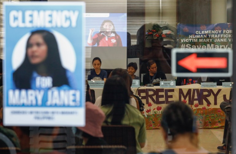 Mary Jane Veloso's parents on their visit to Indonesia earlier in June. They are seated at a table, People are holding banners calling for their daughter's freedom 