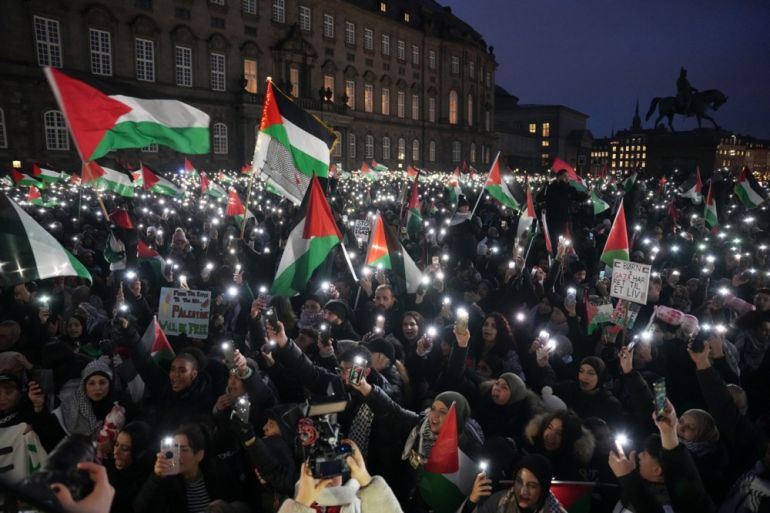 People light up their phones as they participate in a pro-Palestinian rally in front of the Danish parliament