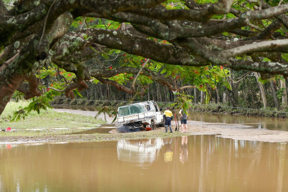 People attempt to rescue a vehicle bogged in mud from the receding floodwaters in Cairns, Queensland, Australia, 18 December