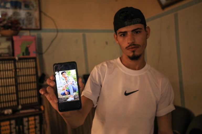 Khader al-Saeedi shows a photo on his phone of his brother Mohammed, who was kidnapped by Israeli soldiers last October