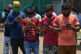 Stranded migrant workers look at their mobile phones as they register for special transportations organized to bring them back to their hometowns during a government-imposed nationwide lockdown as a preventive measure against the spread of the COVID-19 coronavirus, in Mumbai, India