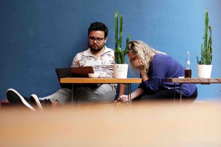 A man uses his computer next to a woman writing a message on her mobile phone at a cafe in Sao Paulo, Brazil October 17, 2017