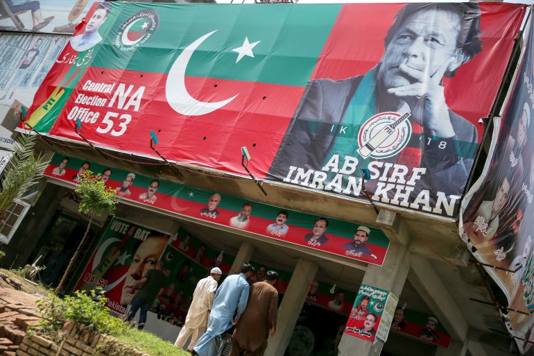 As pessoas passam por uma imagem do astro do críquete que virou político Imran Khan, presidente do Paquistão Tehreek-e-Insaf (PTI) em um mercado