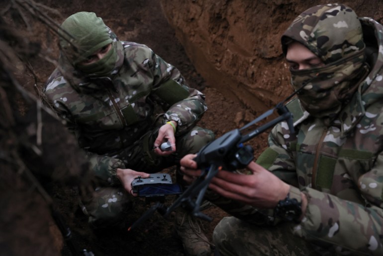 Two soldiers with the 58th Independent Motorized Infantry Brigade of the Ukrainian Army who wanted to be identified as "Ghost", 24, and "Soap", 30, arm a drone with a modified grenade to test it, as Russia's invasion of Ukraine continues, near Bakhmut, Ukraine, November 25, 2022