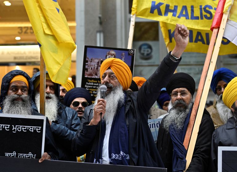 A demonstrator uses a microphone as others hold flags and signs as they protest outside India's consulate, a week after Canada's Prime Minister Justin Trudeau raised the prospect of New Delhi's involvement in the murder of Sikh separatist leader Hardeep Singh Nijjar, in Vancouver, British Columbia, Canada September 25, 2023. REUTERS/Jennifer Gauthier
