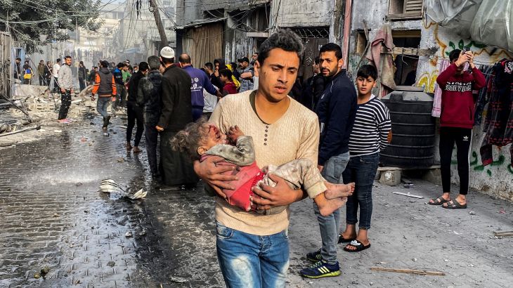 A Palestinian carries an injured child following an Israeli strike on a house, after a temporary truce between Hamas and Israel expired, in Rafah, in the southern Gaza Strip December 1, 2023.