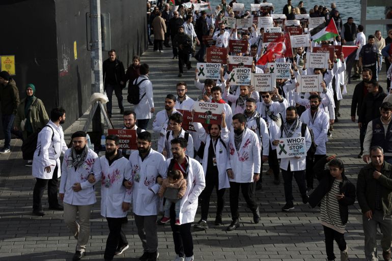 a crowd of people in white coats with hands marking red paint walking in rows