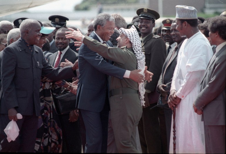 Nelson Mandela (L) is embraced by PLO leader Yasser Arafat as he arrives at Lusaka