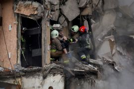 Emergency personnel evacuate a woman at the site where an apartment block was heavily damaged by a Russian missile strike, amid Russia's attack on Ukraine, in Dnipro, Ukraine January 15