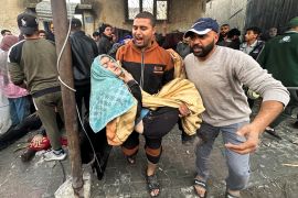 Palestinians carry an injured person following an Israeli attack on houses in Rafah in southern Gaza, December 12, 2023 [Fadi Shana/Reuters]