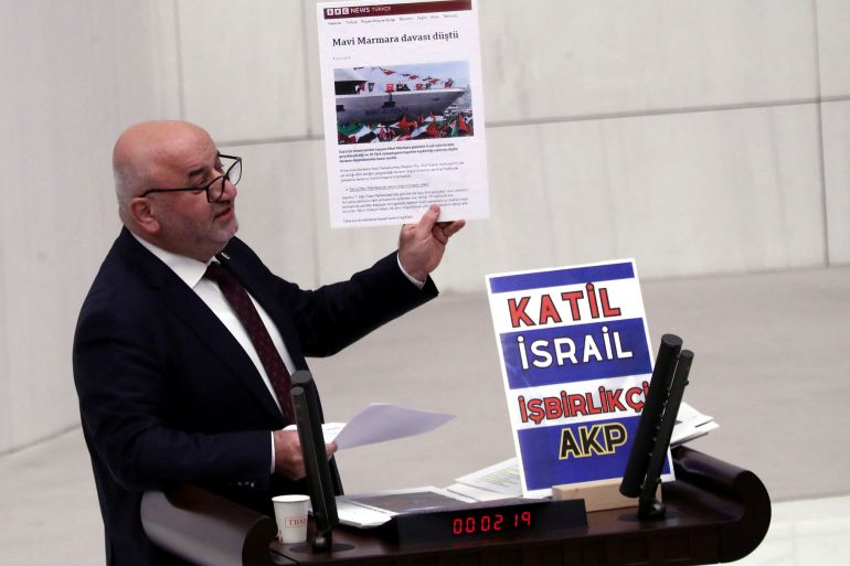Turkey's opposition Felicity Party (Saadet) lawmaker Hasan Bitmez makes a speech at a stand with a placard, criticizing the government's policy towards Israel, at the Turkish parliament in Ankara