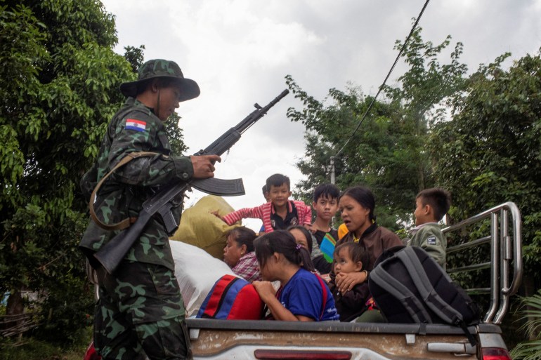 Civilians sitting in the back of a truck. A soldier form the Karenni Nationalities Defence Force is standing on one side.