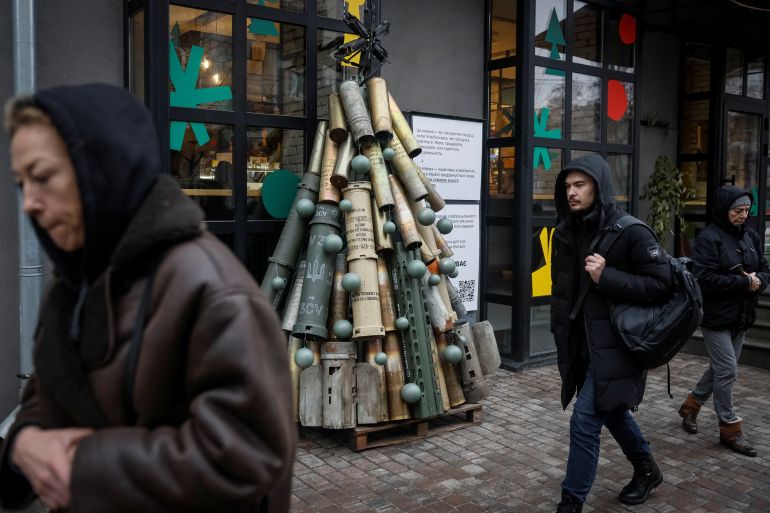 People pass by a symbolic Christmas tree made from used artillery shells and parts of rockets in Kyiv