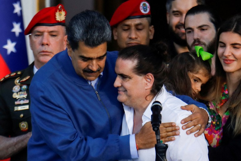 Nicolas Maduro hugs Alex Saab after he arrived back in Venezuela following a prisoner swap deal with the US. They are smiling. Other people are standing behind them.
