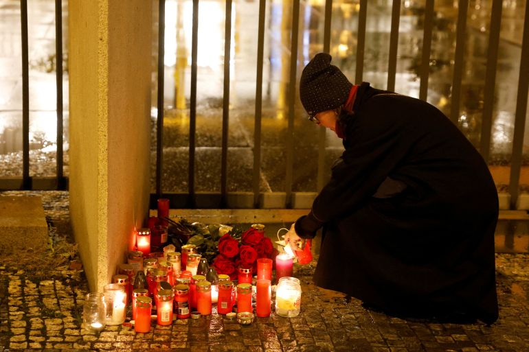 A woman lighting candles outside Charles University after the shooting