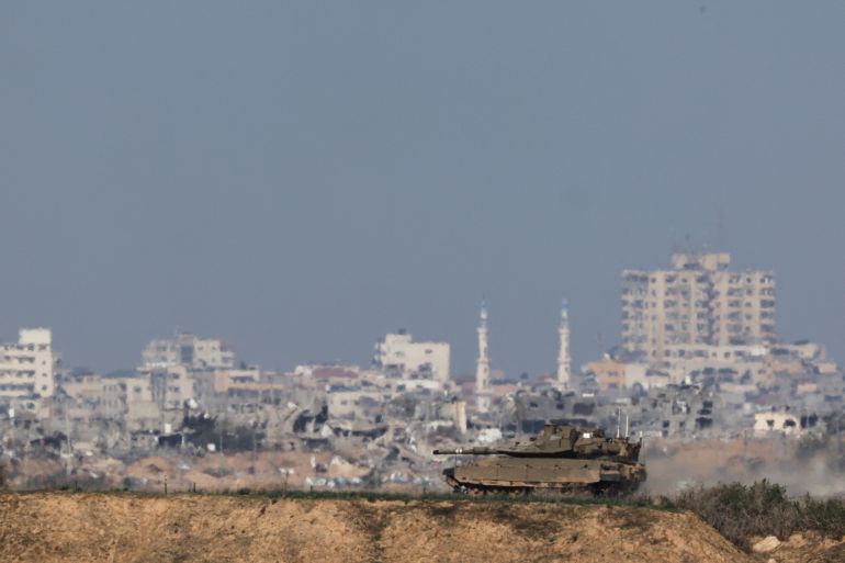An Israeli military vehicle operates in Gaza, amid the ongoing conflict between Israel and the Palestinian Islamist group Hamas, as seen from southern Israel, December 24