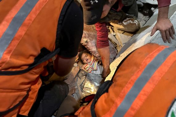 Kurtarma görevlileri, İsrail grevinde vurulan bir evin enkazı altından Filistinli bir çocuğu çıkarmaya yardım ediyor