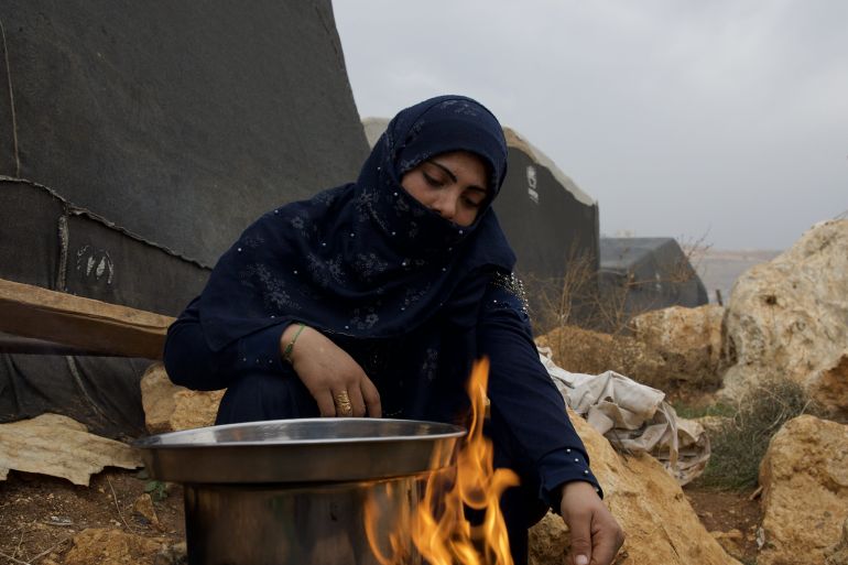 Yasmin Alhamou cooking over an open fire in a displacement camp