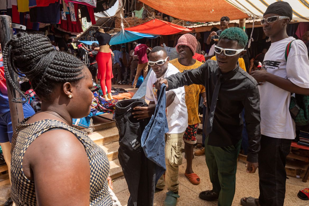 Vendors display second-hand clothes to a buyer inside a market in Kampala.