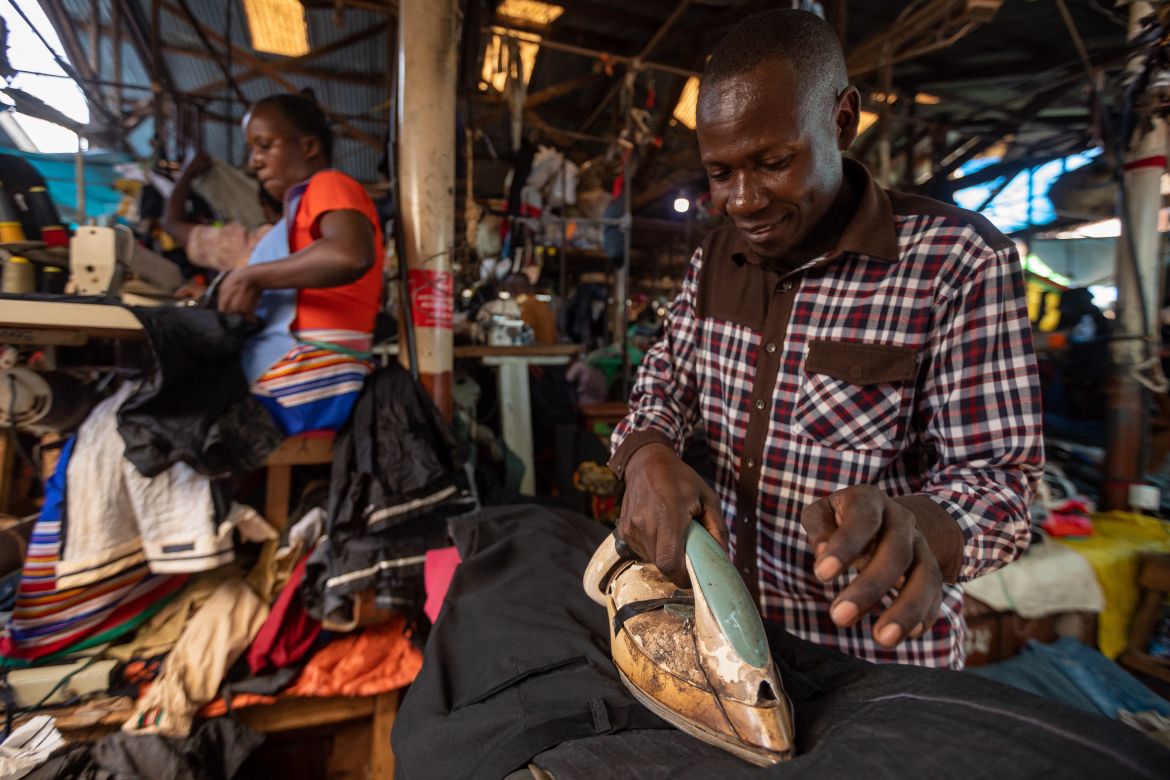 A man irons second -hand clothes before displaying them to be sold at a market in Kampala.