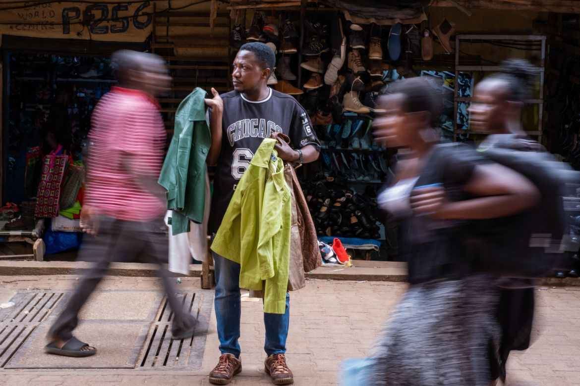 A man selling second-hand clothes stands while waiting for costumers at a market in Kampala.