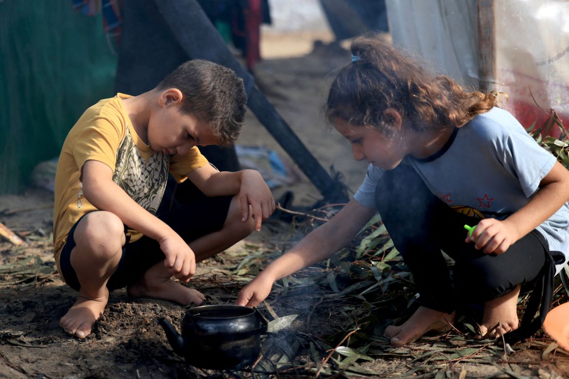 Internally displaced Palestinian children, who fled from the Israeli bombardment of the northern Gaza Strip and are now living in make shift shelters, light a fire to boil a kettle after overnight rainstorms in Khan Yunis, in the southern Gaza Strip.