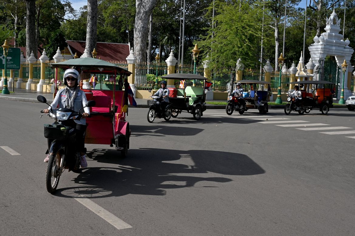 This photo taken on November 17, 2023 shows female Tuk Tuk drivers driving along a street in Siem Reap province.