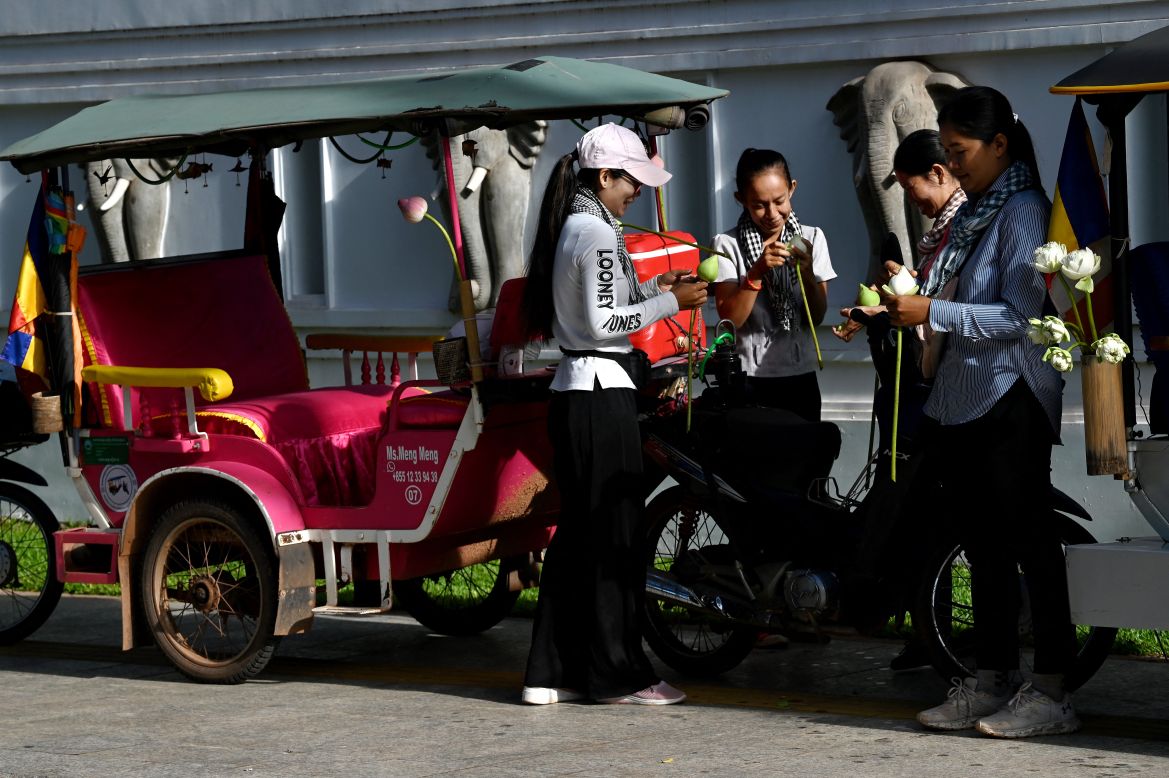 This photo taken on November 17, 2023 shows female Tuk Tuk drivers decorating lotus flowers for their Tuk Tuks in front of a hotel in Siem Reap province.