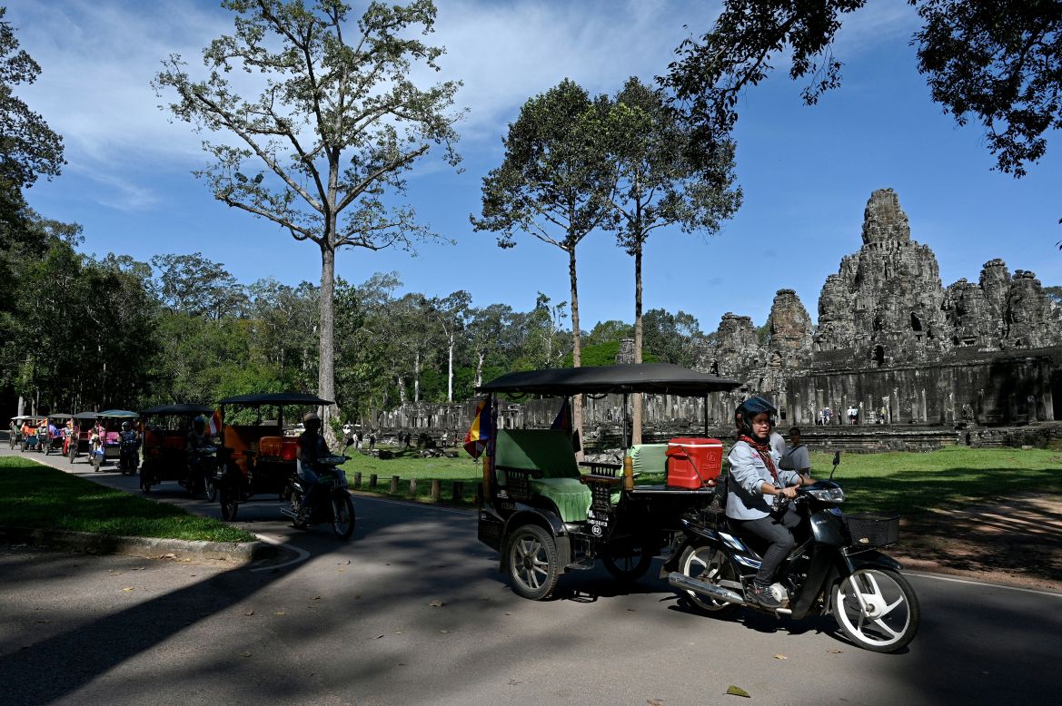 This photo taken on November 17, 2023 shows female Tuk Tuk drivers driving near the Bayon temple at the Angkor complex in Siem Reap province.