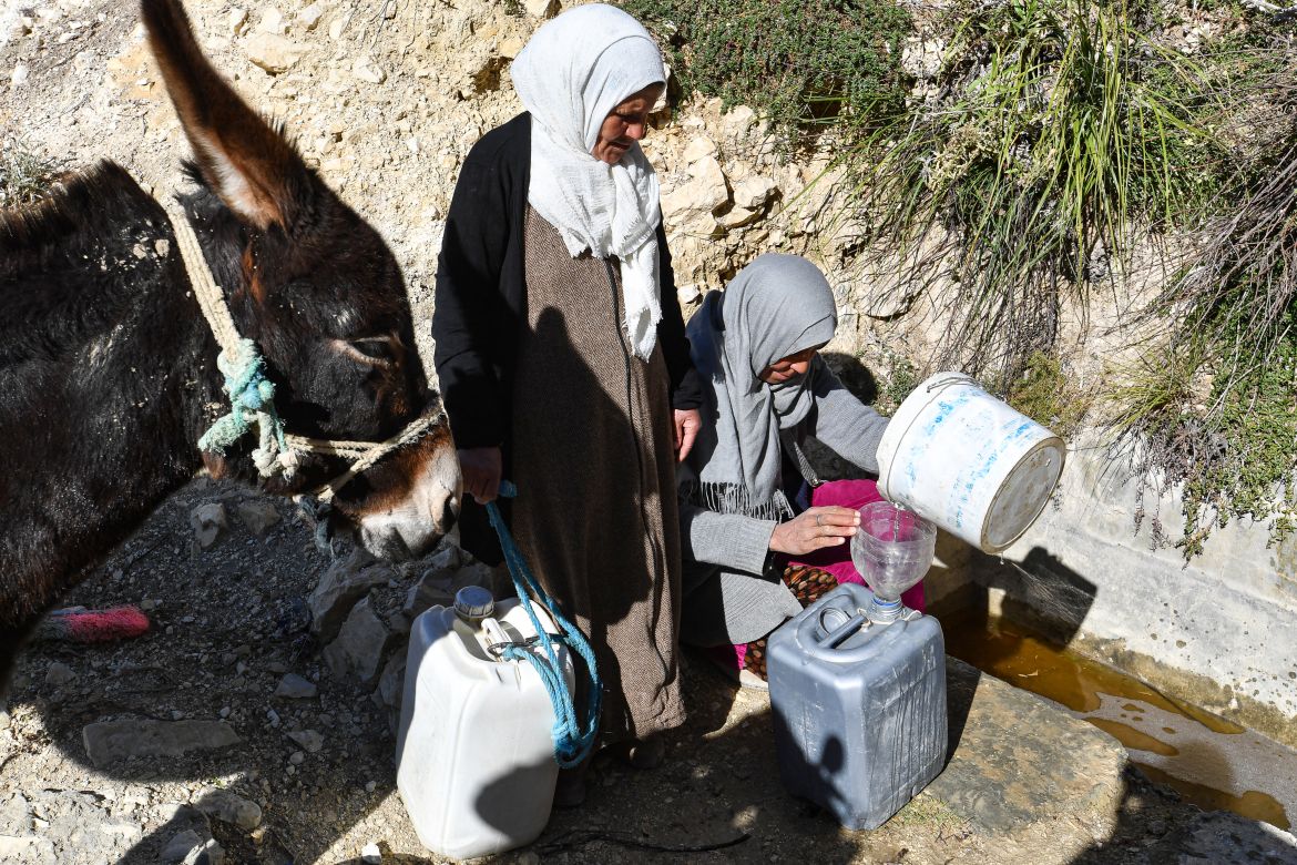 Tunisian women fill their plastic jerry cans with water from a river in the remote village of Ouled Omar