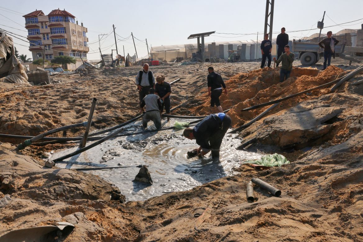 Palestinian workers repair a damaged water pipe following an Israeli airstrike on the main road between Rafah and Khan Yunis on the southern Gaza Strip.