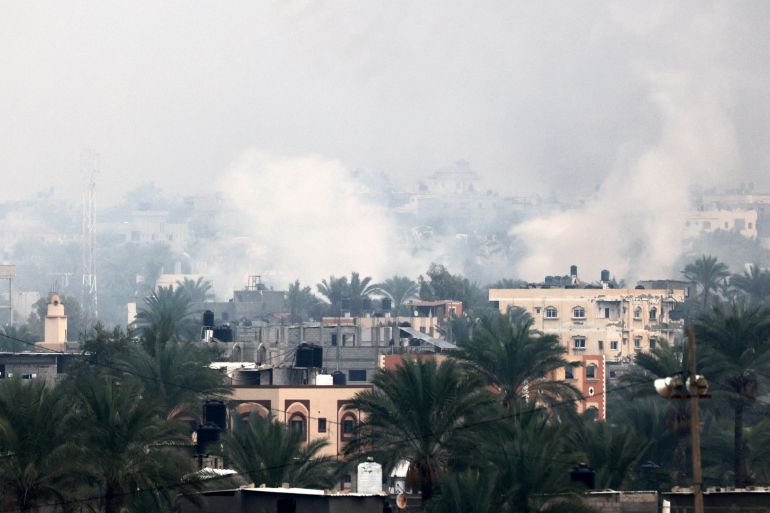 Smoke rises above buildings in Khan Yunis in the southern Gaza Strip, as battles between Israel and Hamas militants continue on December 5