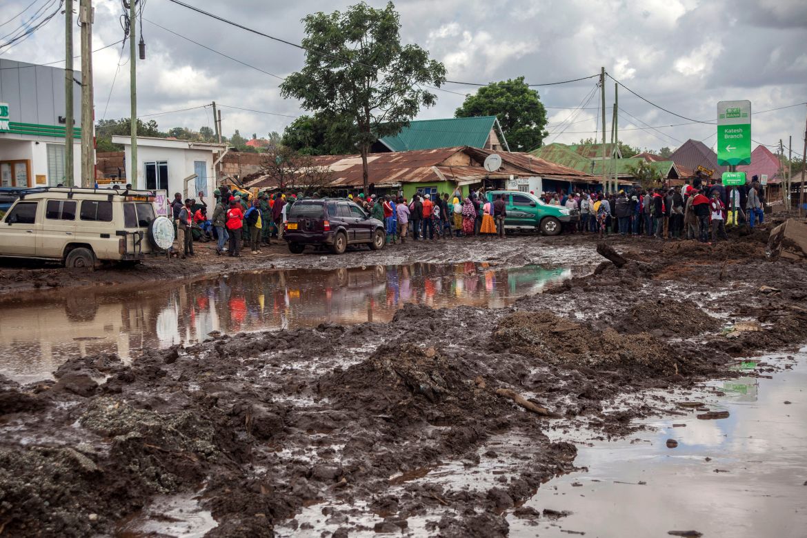People gather to assess damages at a street covered on mud following landslides and flooding triggered by heavy rainfall in Katesh, Tanzania.