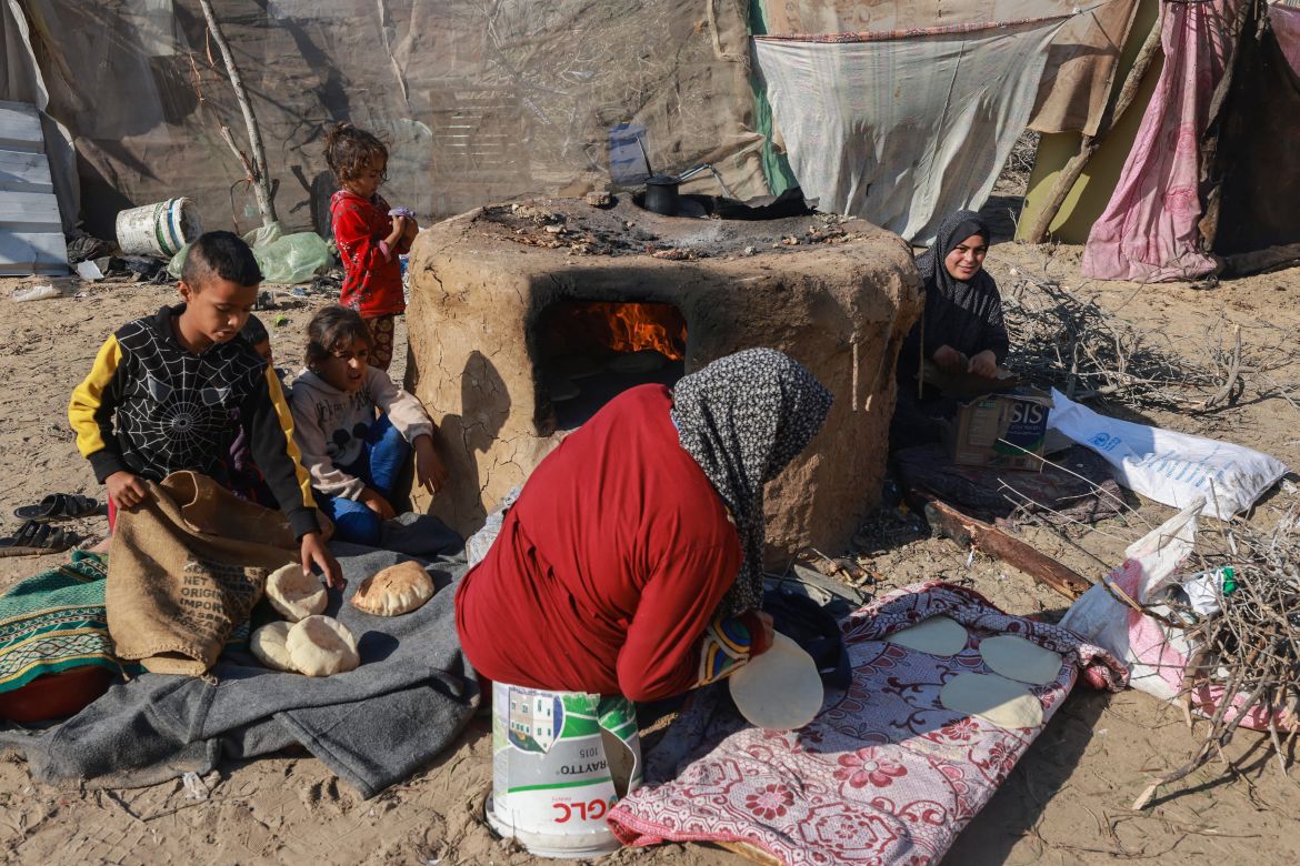 A displaced Palestinian woman and children who fled Khan Yunis, cook break in Rafah further south near the Gaza Strip's border with Egypt.