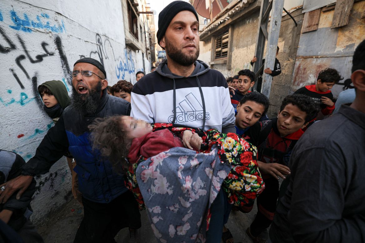 A member of the al-Hopi family carries the body of a child killed during Israeli bombardment overnight in Rafah on the southern Gaza Strip.