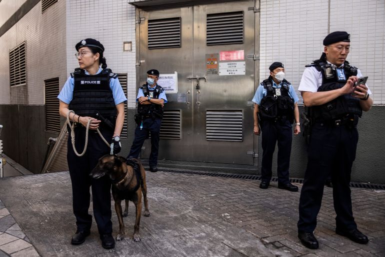 Four police officers standing guard outside a polling station in Hong Kong. One has a dog on a leash.