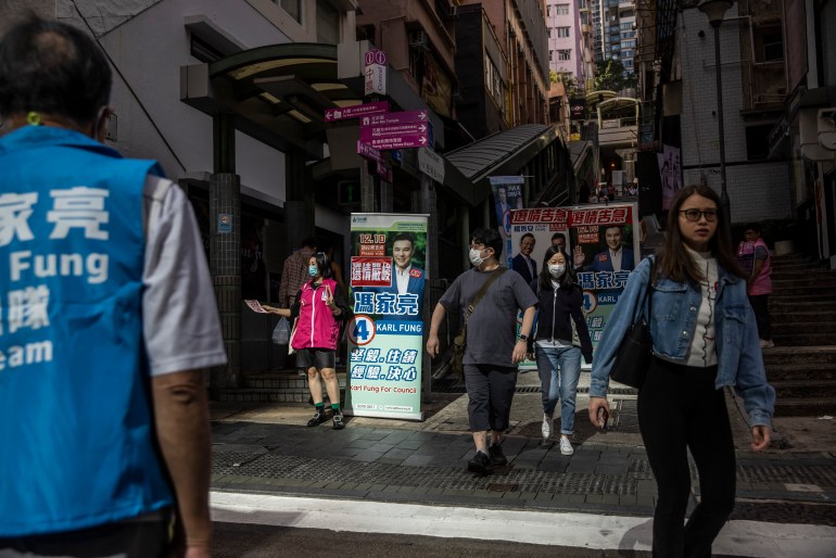 People in Hong Kong walking past banners for district council candidates