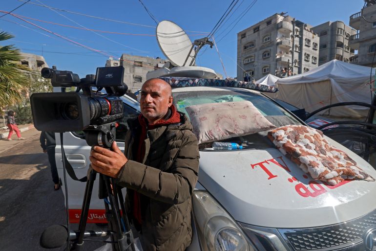 A journalist works outside his vehicle near a makeshift shelter in Rafah on the southern Gaza Strip on December 11, 2023