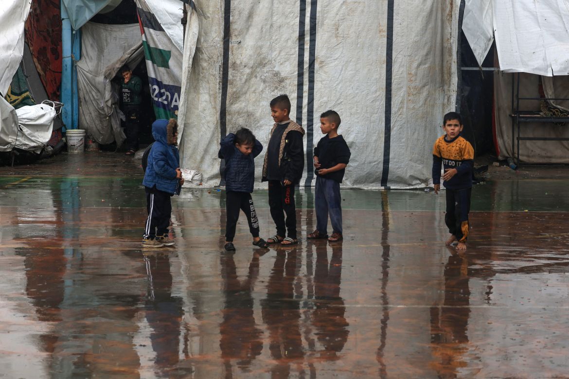 Palestinian children play amidst the rain at camp for displaced people in Rafah, in the southern Gaza Strip, where most civilians have taken refuge as battles continue between Israel and the Palestinian militant group Hamas.