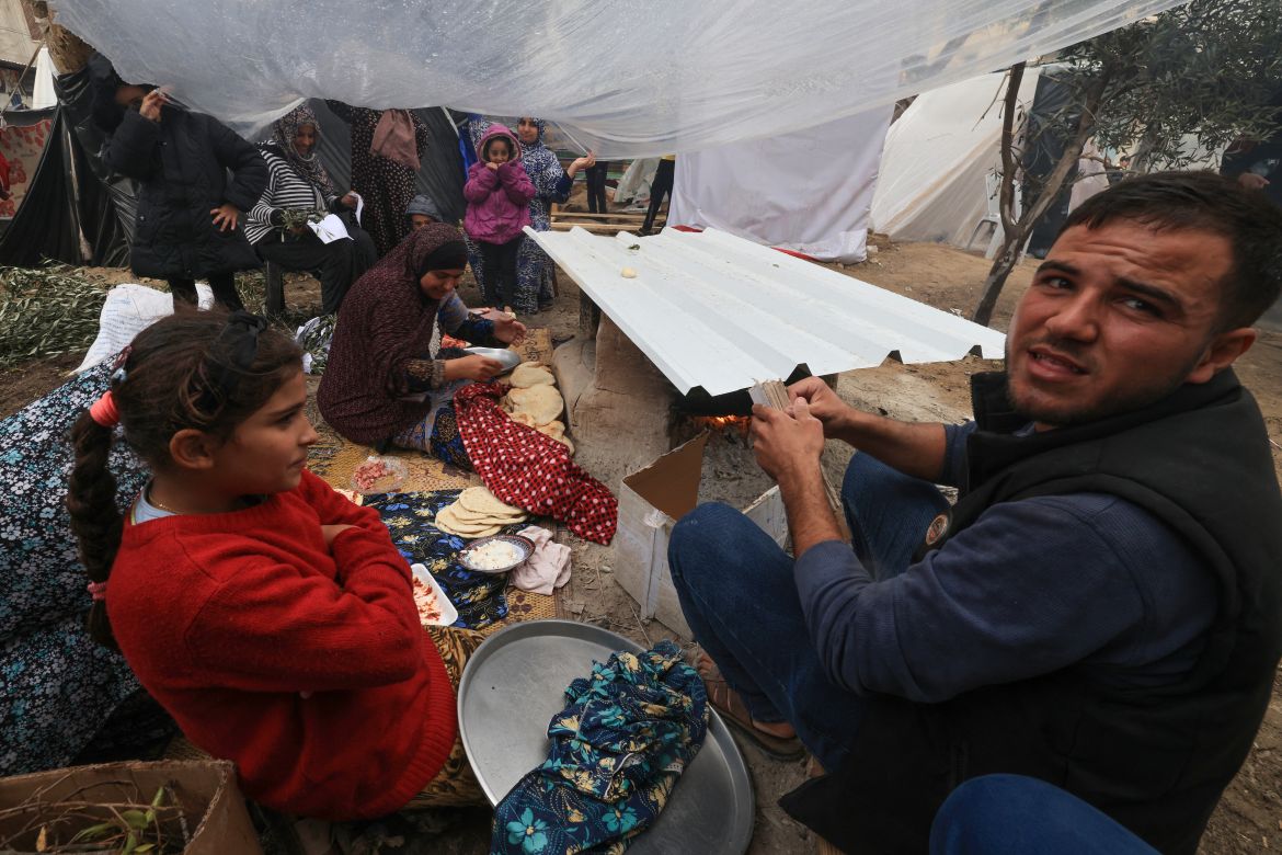 Palestinians sit inside a tent as they cook amidts the rain at camp for displaced people in Rafah, in the southern Gaza Strip, where most civilians have taken refuge.