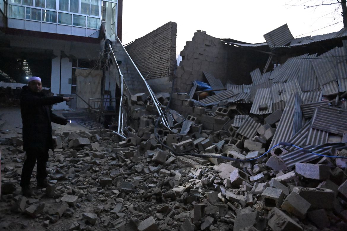 A resident looks at a collapsed building